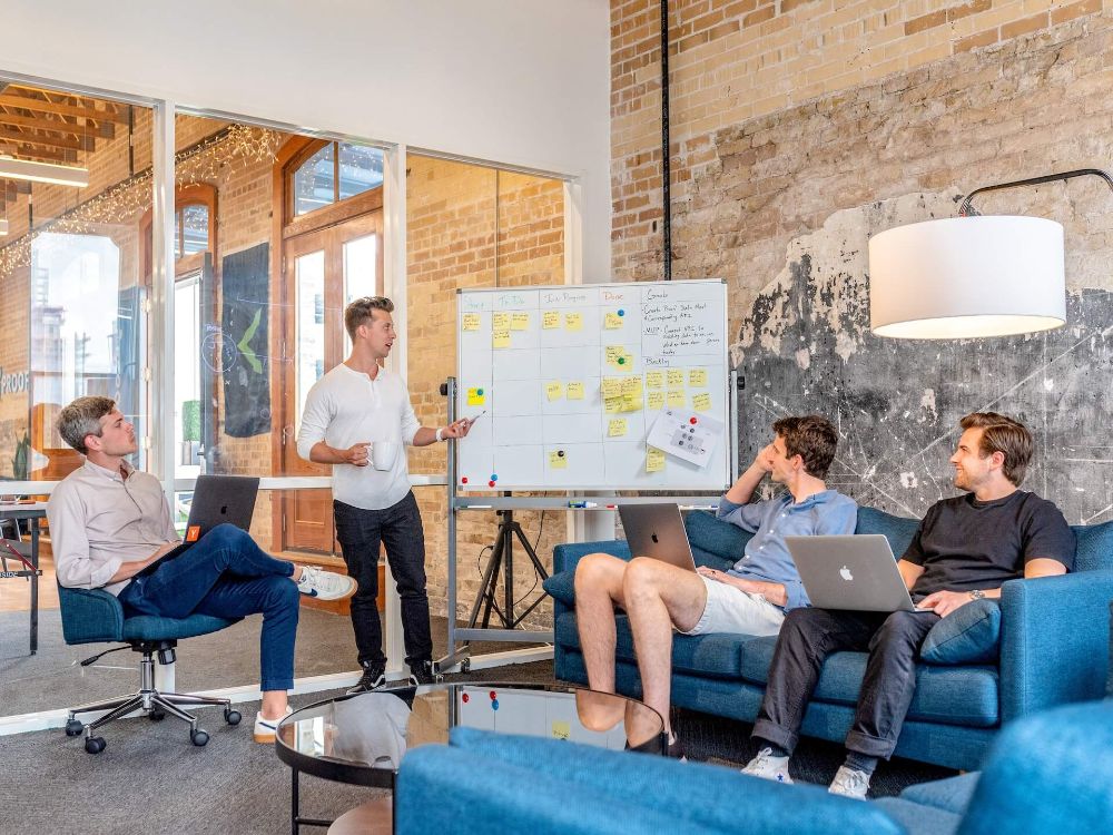 Colleagues discussing a plan on a whiteboard in a bright office